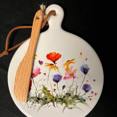 Round white ornament with painted wildflowers and a wooden spoon tied on