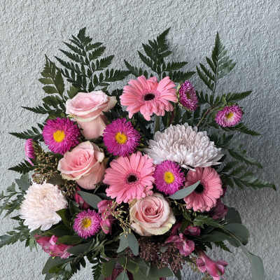 Pink roses and gerbera daisies in a purple glass vase