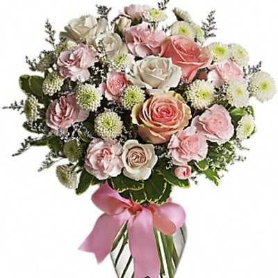 Pink and white rose bouquet in a clear glass vase with a pink ribbon