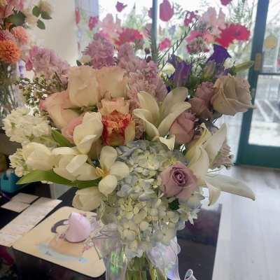 Pastel bouquet of roses, lilies, and hydrangeas in a glass vase