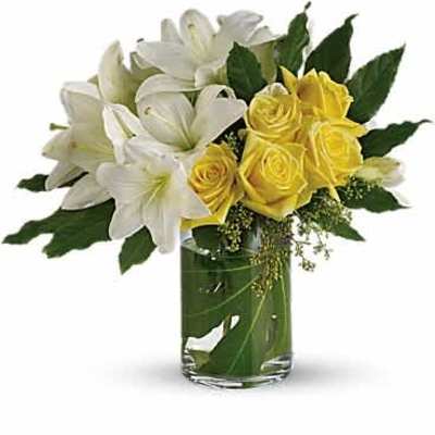 Arrangement of white lilies and yellow roses in a clear glass cylinder vase