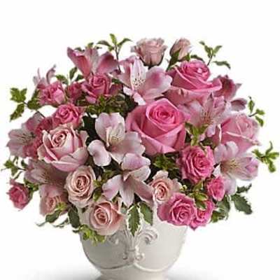 Pink roses and alstroemeria arranged in a white ceramic pedestal vase
