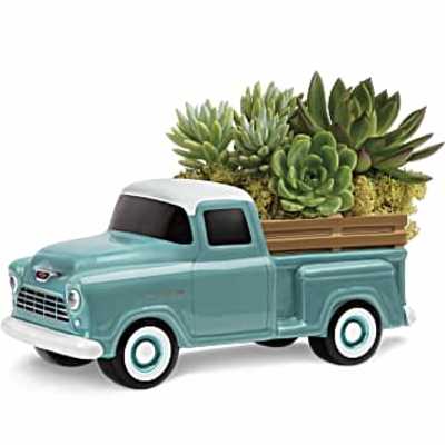 Vintage teal ceramic truck planter filled with assorted green succulents