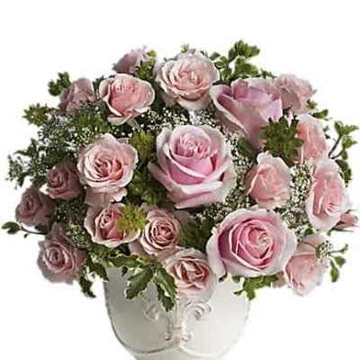 Round arrangement of light pink roses in an ornate white footed vase