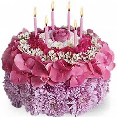 Round pink floral arrangement styled like a birthday cake with candles on top