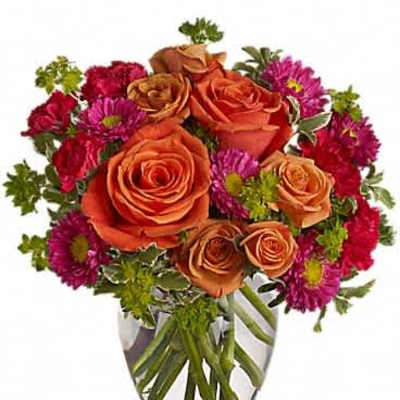 Round bouquet of orange roses and hot pink mums in a clear glass vase
