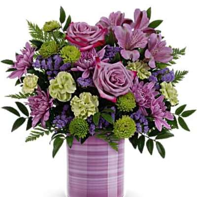 Lavender and green mixed flower arrangement with roses and mums in a striped lavender cylinder vase