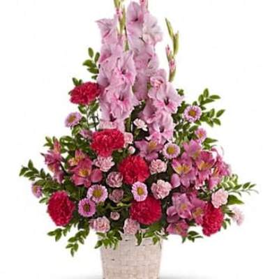 Tall pink and red mixed flower arrangement in a white woven basket