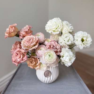 Pink and white flowers arranged in a white vase