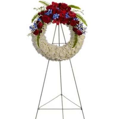 Standing white wreath with red and blue flowers on a metal easel