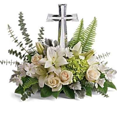 Low white lily and rose arrangement with green accents surrounding a crystal cross.