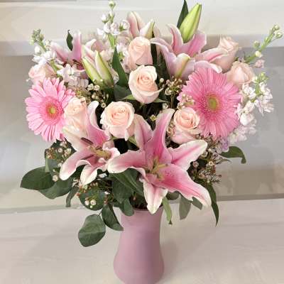 Pink lilies, roses, and gerbera daisies in a pink vase