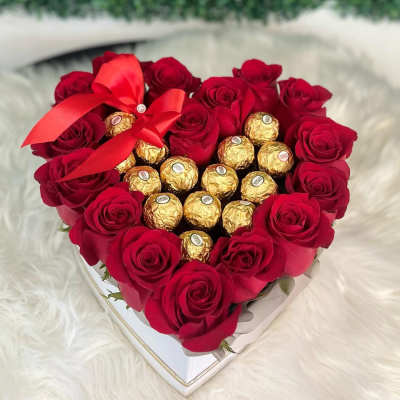 Heart-shaped box of red roses with gold-wrapped chocolates and a red ribbon