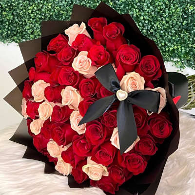 Large bouquet of red and blush roses wrapped in black paper with a black ribbon
