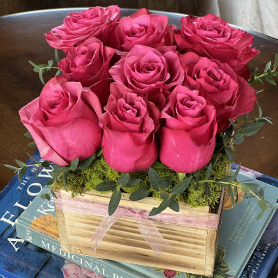 Pink roses arranged in a wooden box with a ribbon