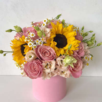 Pink roses and sunflowers in a pink cylindrical vase