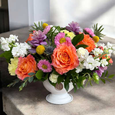 Colorful mixed flower arrangement in a white pedestal vase