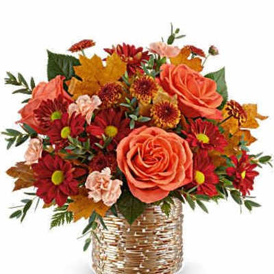 Bouquet of orange roses and red daisies in a woven basket