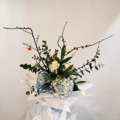 Bouquet of white roses, blue hydrangeas, and white tulips with branching stems