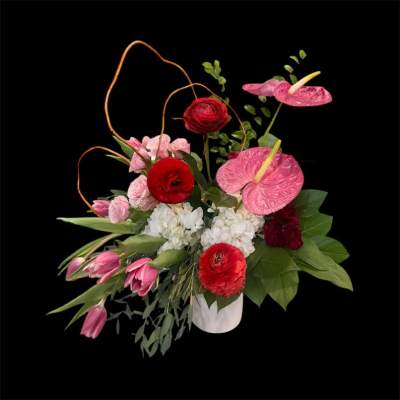 Pink and red floral arrangement in a white vase with tall curved stems