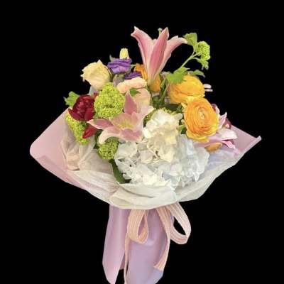 Pastel bouquet with lilies, hydrangea, and ranunculus wrapped in pink paper