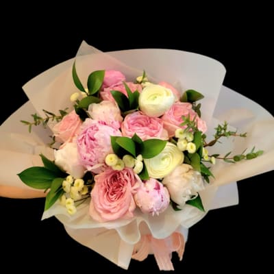 Pink and white bouquet of roses and peonies wrapped in white paper