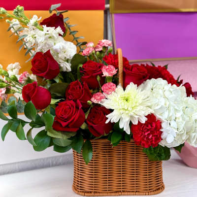 Basket arrangement of red roses, white hydrangeas, and white chrysanthemums