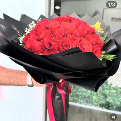 Bouquet of red roses wrapped in black paper with a pink ribbon
