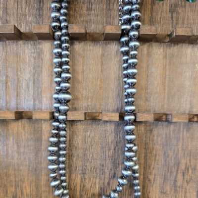 Two strands of metallic silver beads hanging on a wooden surface