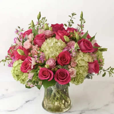 Pink roses and pale green hydrangeas in a clear glass vase