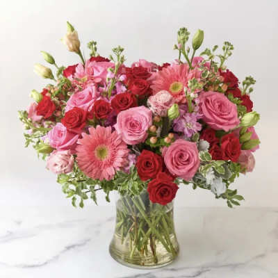 Pink and red rose bouquet with gerbera daisies in a clear glass vase