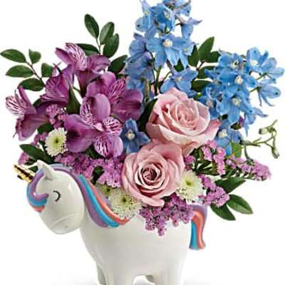 Playful arrangement of pink roses, purple blooms, and blue flowers in a white unicorn ceramic container