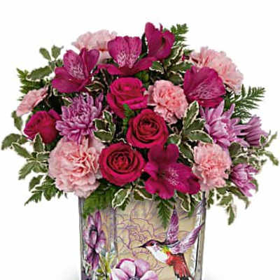 Pink and purple mixed flower arrangement in a square glass vase with a hummingbird and floral illustration.