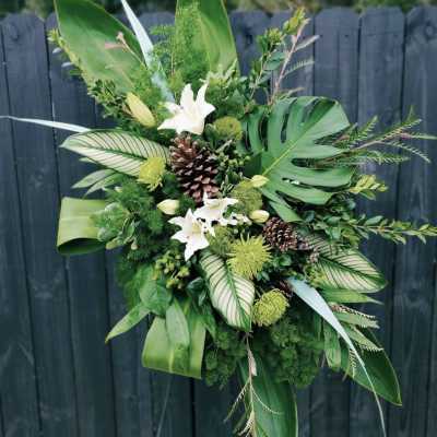 Tropical green floral arrangement with white lilies and pinecones