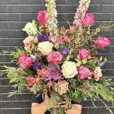 Large mixed bouquet of pink, white, and purple flowers in a glass vase