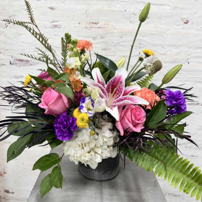 Mixed bouquet in a black vase with pink roses and a pink lily