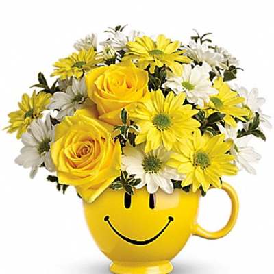 Yellow roses and daisies in a smiley-face mug