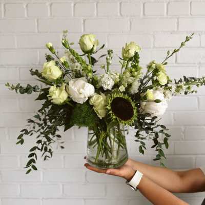 White and pale green floral arrangement in a glass vase