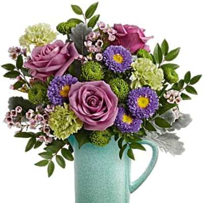 Purple roses and mixed flowers arranged in a turquoise pitcher vase
