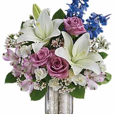 Bouquet of white lilies, pink roses, and blue flowers in a silver vase