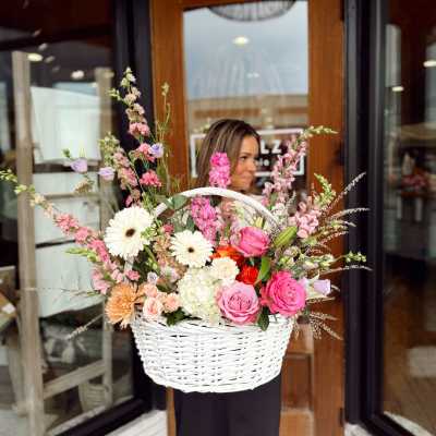 Woman holding a large white basket of pink and white flowers