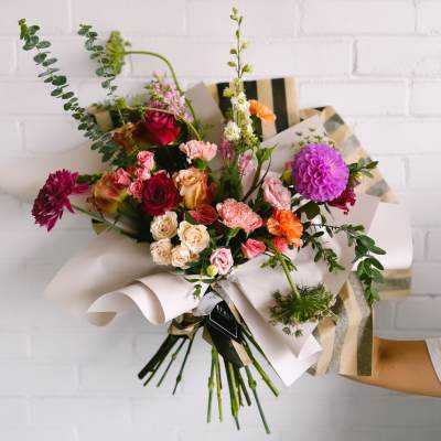 Mixed bouquet of roses, carnations, and dahlias wrapped in paper