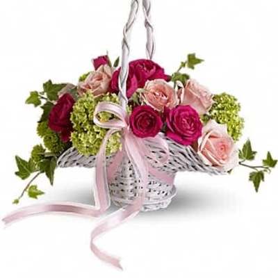 White wicker basket of hot pink and pale pink roses with green blooms and a pink ribbon bow.