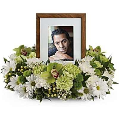 Low ring of white and green flowers encircling a wooden photo frame.