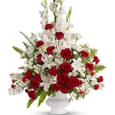 Tall red and white flower arrangement with roses, lilies, and carnations in a white urn vase