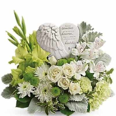 White and green floral arrangement with angel-wing memorial plaque in a low container