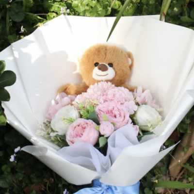 Pink and white bouquet with a teddy bear in white wrapping