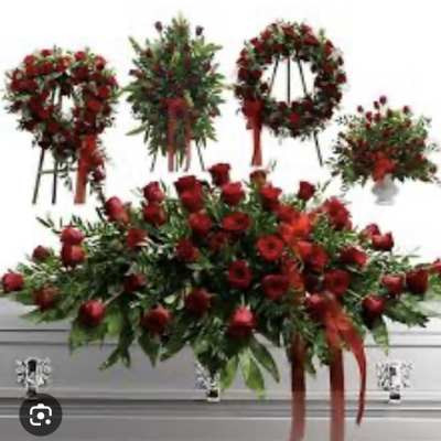 Red rose funeral sprays and wreaths arranged around a casket