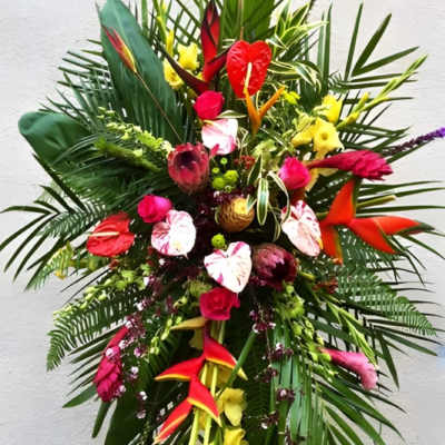 Tall tropical flower arrangement with red, pink, and yellow blooms