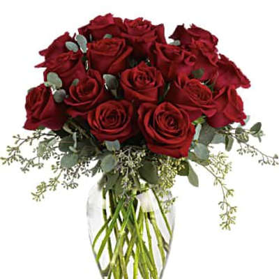 Arrangement of long-stemmed red roses with filler in a clear glass vase